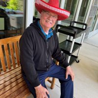 San Jose Senior sitting on a bench, smiling and wearing a sombrero